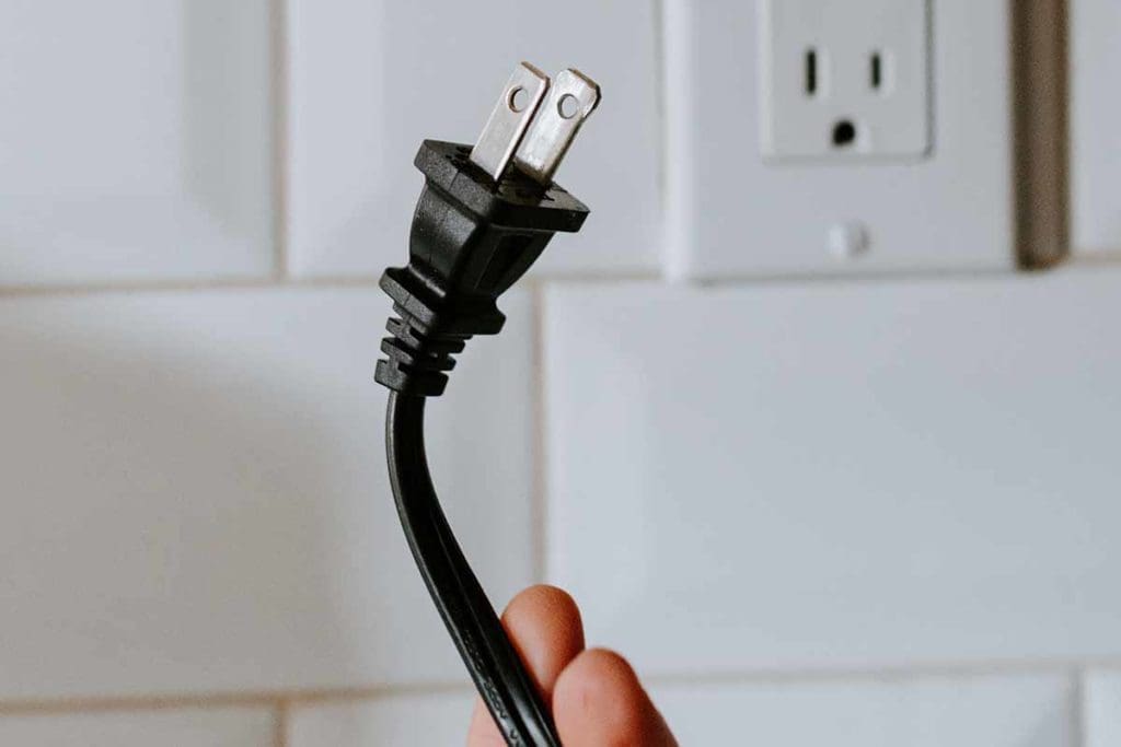 electric plug being held in front of electric outlet